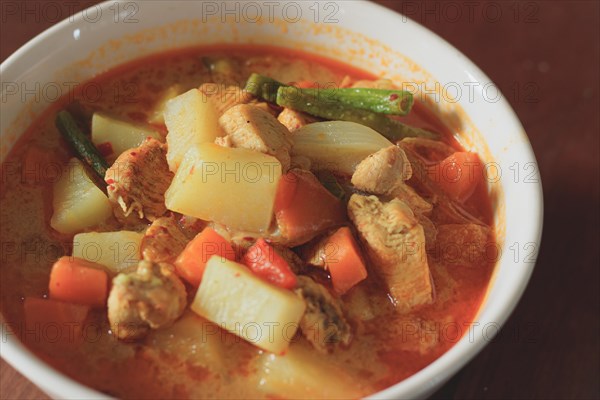 A bowl of hearty chicken curry with potatoes and carrots