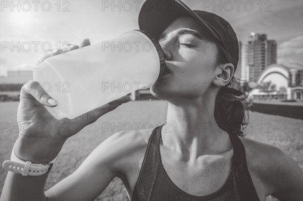 Image of a girl drinking from a bottle after a run. Running concept.