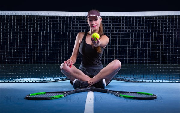 Portrait of a beautiful tennis player sitting on the court. Sports concept.