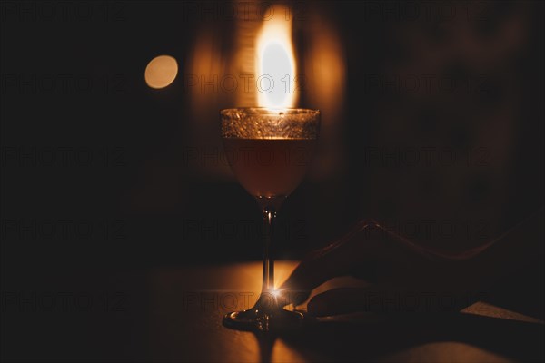 Image of a glass with a cocktail in a night bar against the background of a fiery heater. Restaurant concept