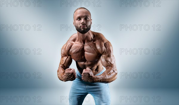 Professional sportsman posing on a blue background. Bodybuilding