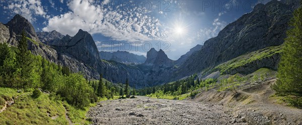 Panorama of a mountain landscape with the sun shining over the peaks