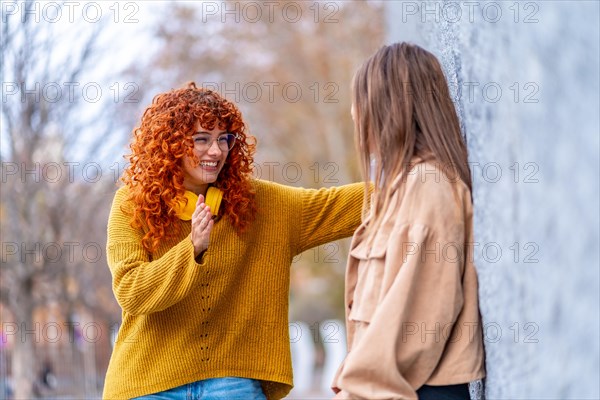 Side view of two smiling women chatting standing in the street