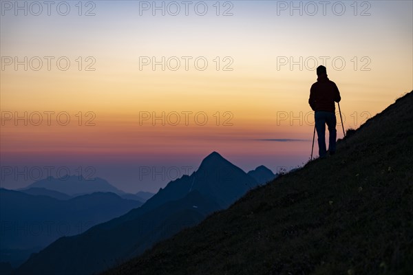 Mountaineer on mountain ridge with Rothorn peak in the background at blue hour