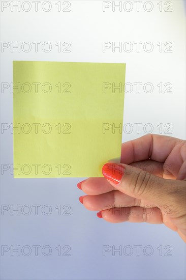 Woman's hand with painted nails holding blank letter paper on pure white background