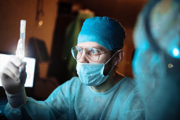 Scientist doctor in a dark laboratory with a test tube of a medicinal product