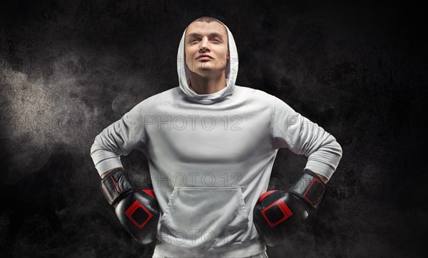 Male trainer posing in the studio with boxing gloves. White hoodie. Mixed martial arts concept. High image quality