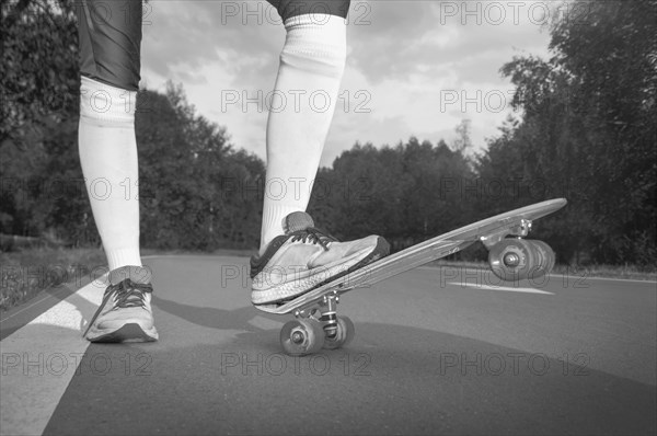 Images of a leg standing on a skateboard. Sunny evening in the park. Skateboarding concept.