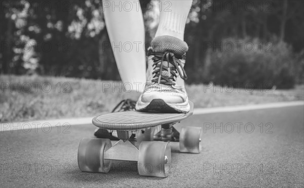 Images of a leg standing on a skateboard. Sunny evening in the park. Skateboarding concept.