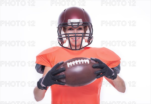 Woman in the uniform of an American football team player posing with a ball on a white background. Sports concept.