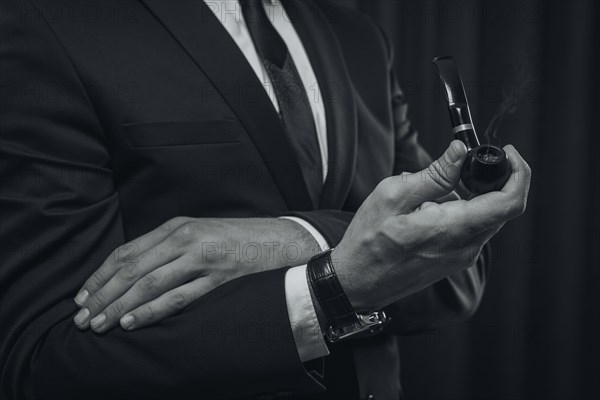 Image of male hands holding a smoking pipe. Tobacco smoking concept.