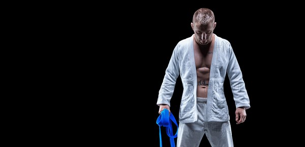 Professional athlete stands in the gym in a kimono with a blue belt. Concept of karate