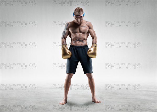 Professional wrestler is standing in a bright room. Mixed martial arts