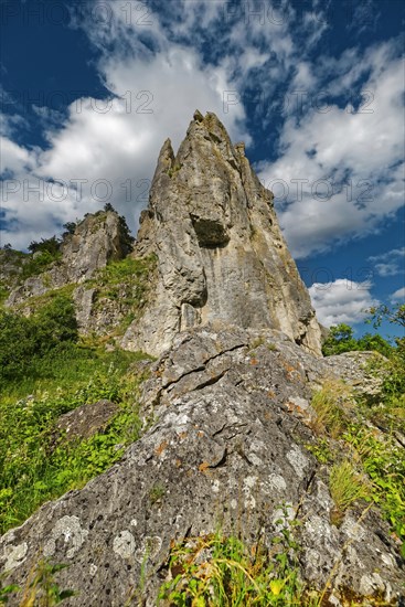 Striking limestone rock formation Burgstein with blue and white sky in the upper Altmuehltal surrounded by green vegetation