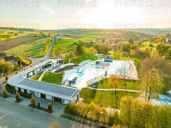 Wide-angle drone shot of an outdoor swimming pool in a rural area during sunset