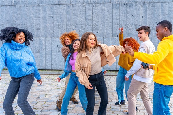 Multi-ethnic young diverse friends dancing together in the street