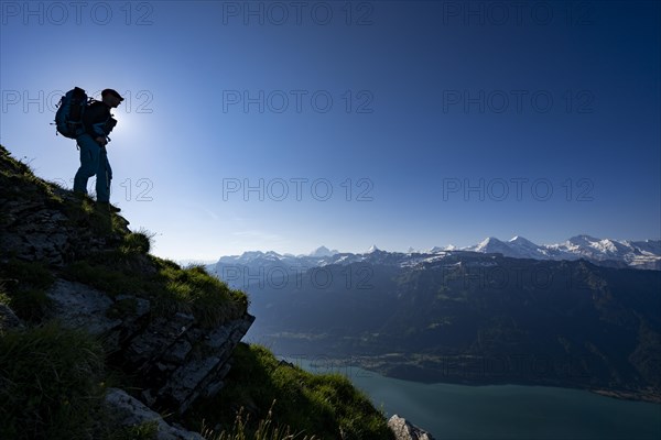 Mountain ridge with mountaineers and Swiss mountains and Lake Thun in the background at sunrise