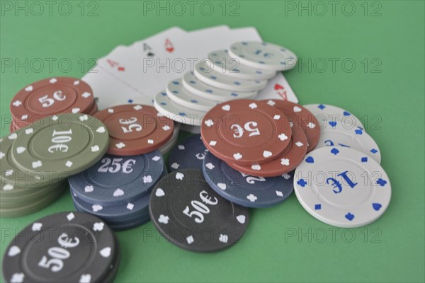 Stacks of poker chips and a fan of playing cards on a green felt gaming table