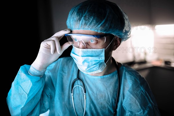 Male scientist doctor working in a laboratory with a monitor in a sterile uniform and glasses