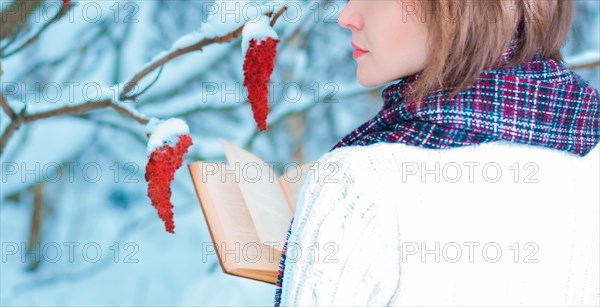 The girl reads a book in the winter forest. Learning concept. Winter's tale.