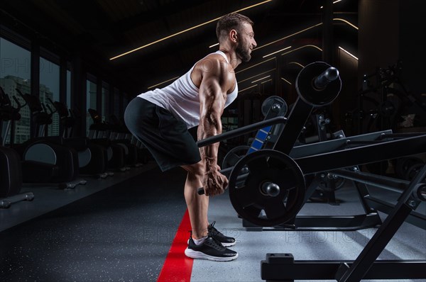 Handsome young man pumps his back in a special machine. Deadlifting. Fitness and bodybuilding concept.