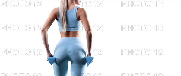 No name portrait of a slender sports girl in blue sportswear with dumbbells. Back view.