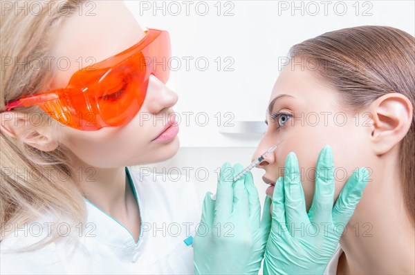 Portrait of the beautician and patient. The doctor injects botox. Skin rejuvenation and lifting concept.