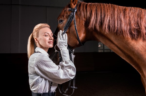 Portrait of a stylish woman hugging a thoroughbred horse. Love and care concept.