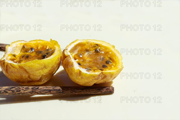 Halved passion fruit and dark wooden spoon on a light background. Close up