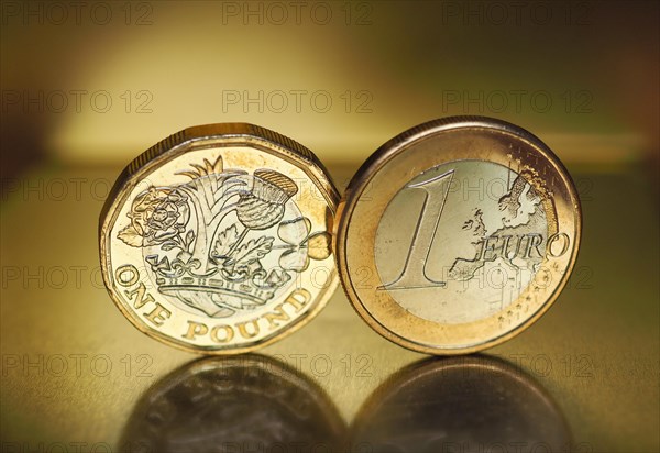 1 pound and 1 euro coin over metal background