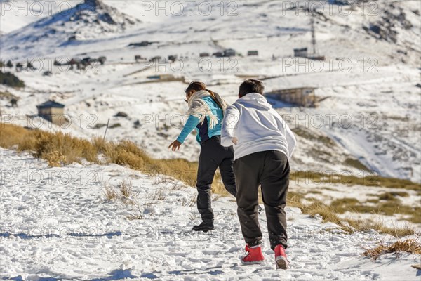 Latin boys running through the snow on a sunny day in the mountains