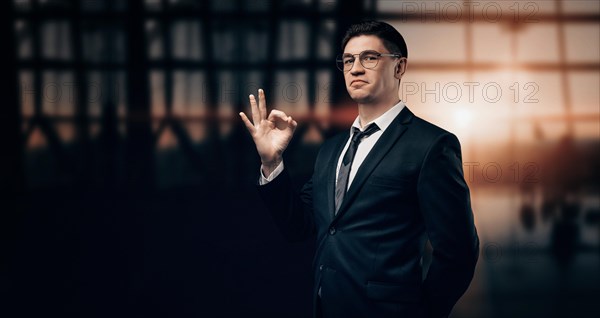 Portrait of a man in a business suit. He is standing at the airport and looking at the camera. Ok sign. VIP transportation. Private airlines. Charter flights.