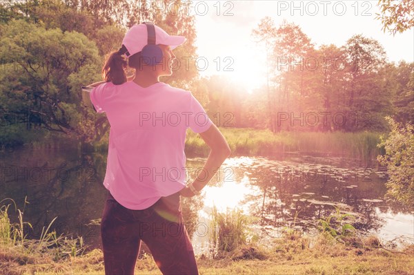 Portrait of a beautiful girl running in a sunny park in headphones with a smartphone. Music apps concept.