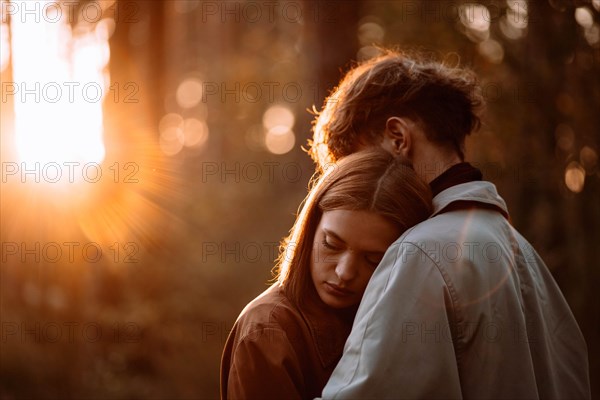 Beautiful fashionable couple in love in the forest at sunset in autumn