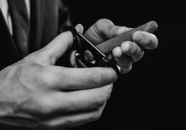 Image of hands holding a guillotine and a cigar. Cigar clubs concept.