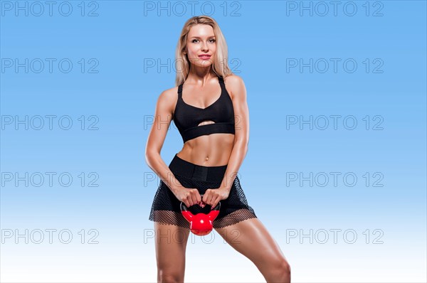 Sportive girl with an ideal figure posing in the studio with dumbbells in her hands.