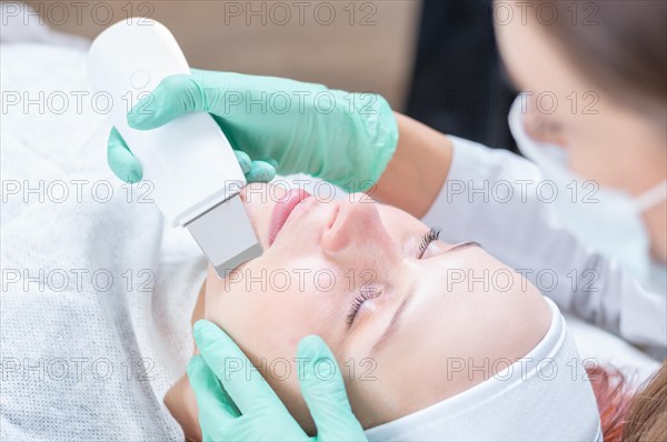 The beautician cleans the patient's face with an ultrasound device. Beauty salons concept.