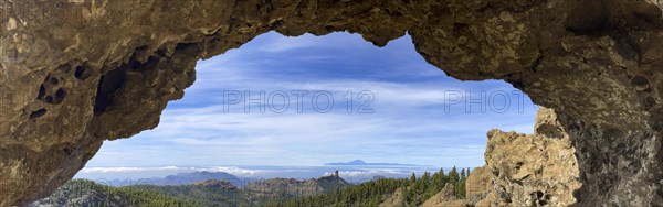 View through a rock arch to Roque Nublo and the Teide mountain peak on the neighbouring island of Tenerife