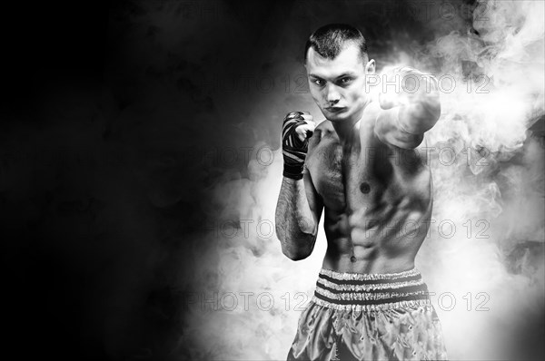 Thai boxer stands in the ring and punches in front of him. The concept of sports