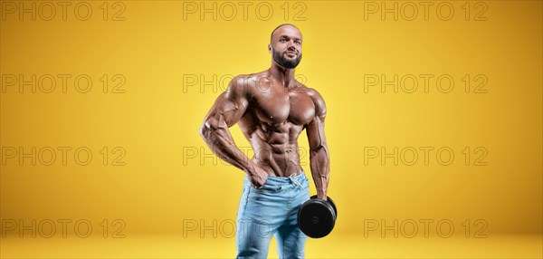 Isolated professional sportsman on a yellow background. Bodybuilding concept. Panorama. Advertising of a gym and sports nutrition.