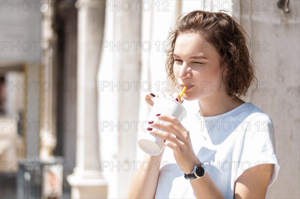 Charming girl drinks lemonade on the street. The concept of tourism