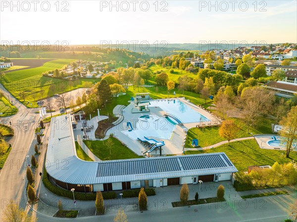 Wide-angle aerial view of a swimming pool with various pools and slides in the evening light