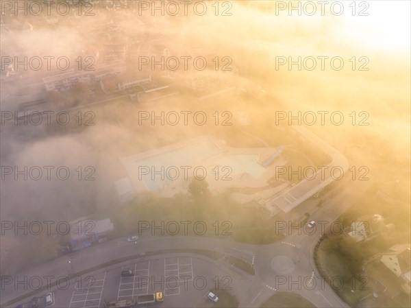Aerial view of a swimming pool covered with a light veil of mist at sunrise
