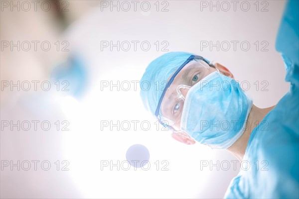 Male surgeon doctor in the operating room looking at the patient at the camera