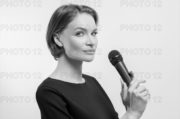 Portrait of an elegant stylish woman with a microphone. White background. Karaoke concept.