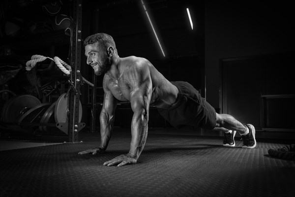 Muscular man doing push-ups in the gym. Fitness concept.