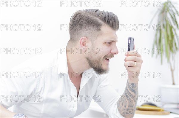 Man in a shirt looks at the smartphone screen in surprise. Concept of unsuccessful betting on games