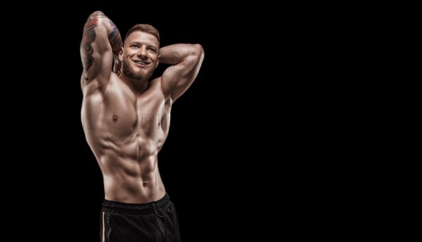 Young muscular guy with nice abs posing on a black background. Fitness and nutrition concept.