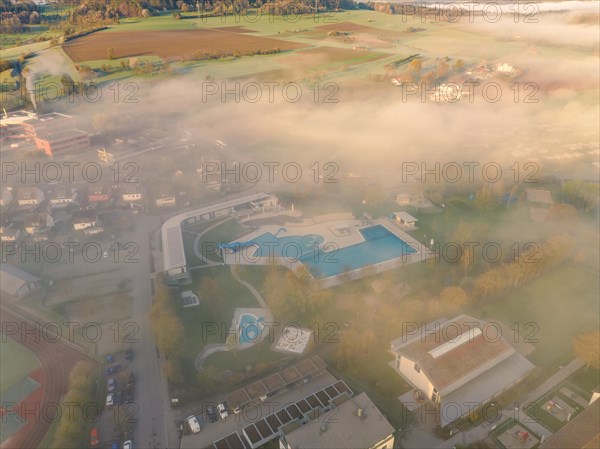 A swimming pool surrounded by fog at dawn