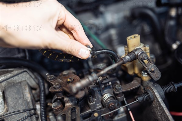 Auto mechanic regulates fuel supply with throttle cable lever